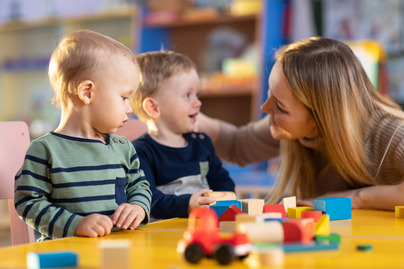 Children building blocks with a teacher in the nursery