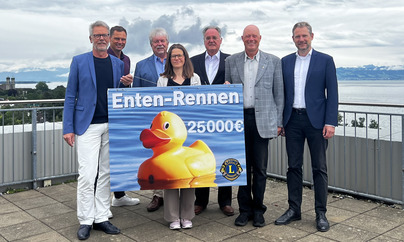 Gruppe vor Bodensee übergibt 25.000€-Scheck „Enten-Rennen“ des Lions Clubs; symbolische Spende für Kinder- und Familienhilfe.