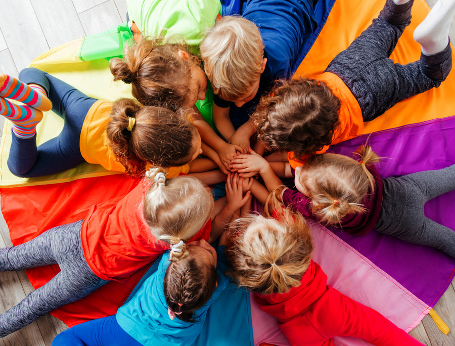 Cheerful children playing team building games on a floor